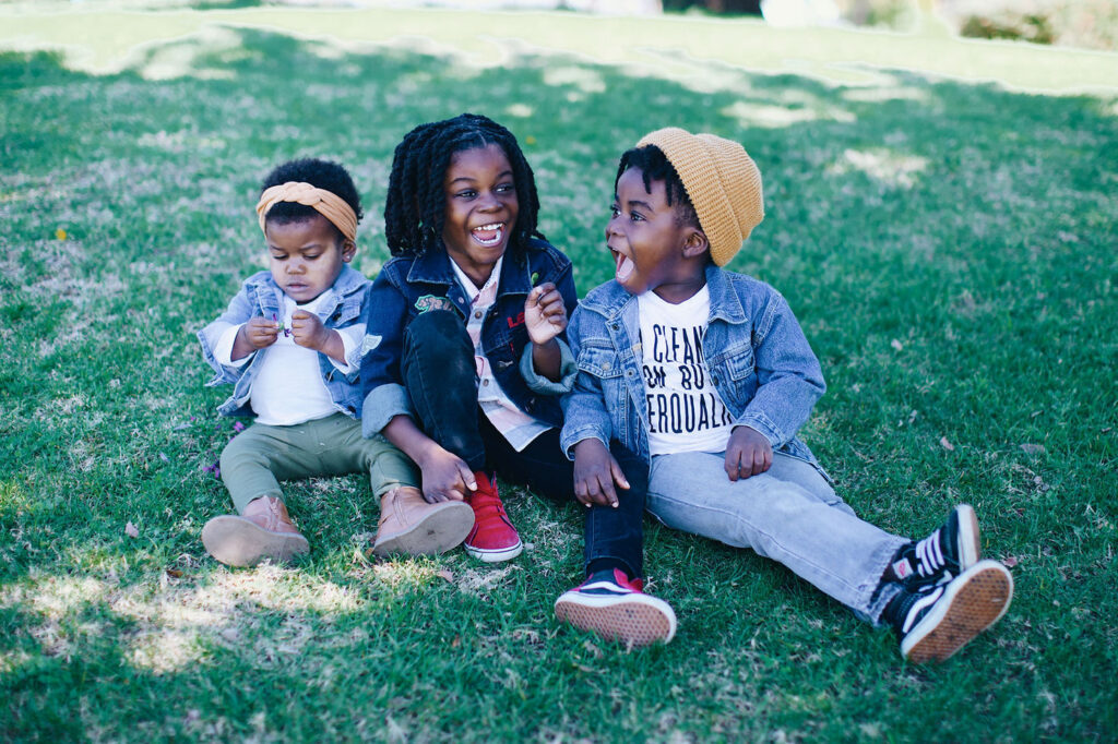 Theo, Uriah, and Anaya Henry sitting in the grass.