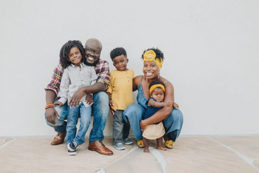 Glen, Yvette, Theo, Uriah, and Anaya Henry smiling for a family portrait in the summer.